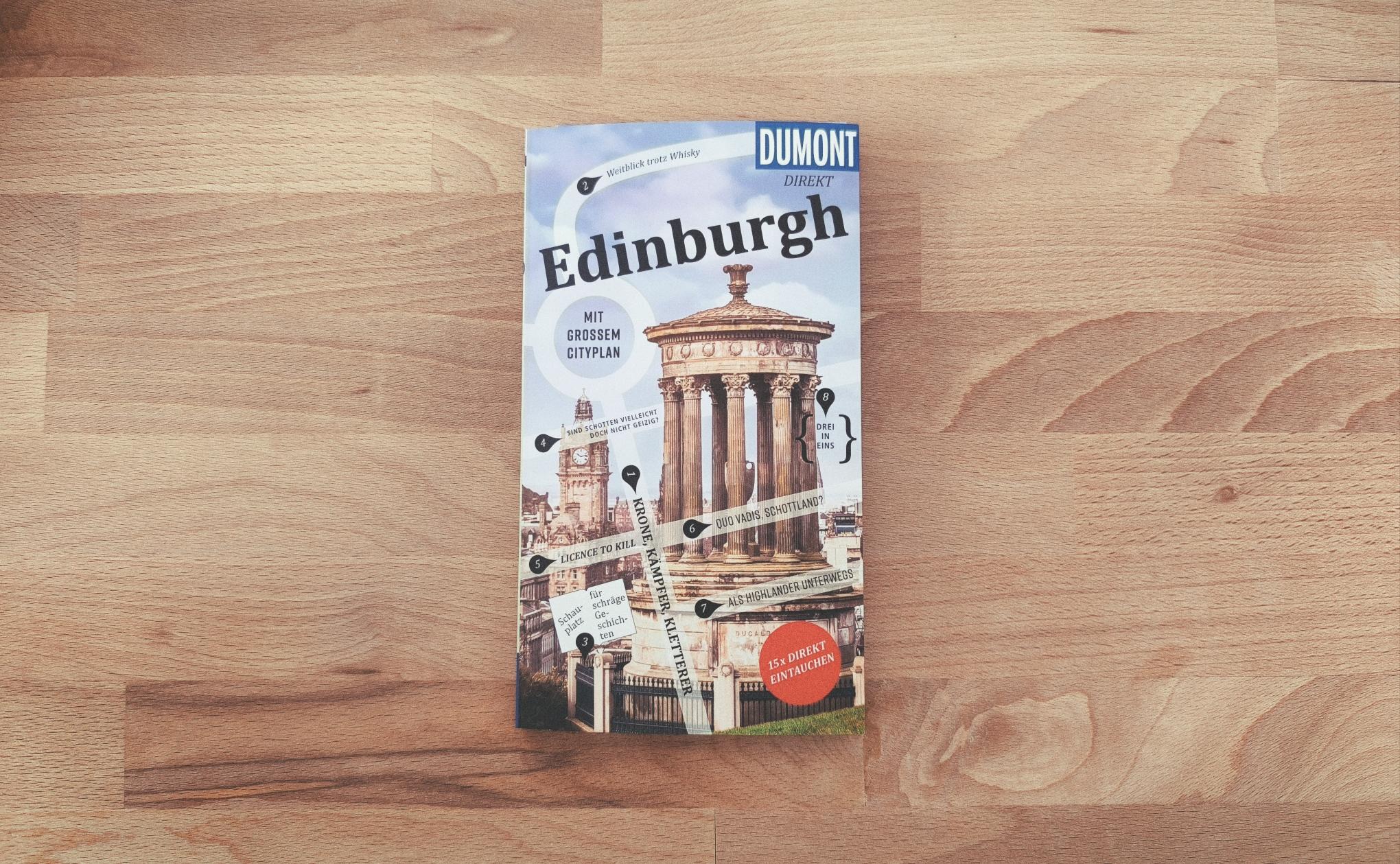 Buch-Reiseführer über Edinburgh von Dumont liegt auf einem Holztisch.